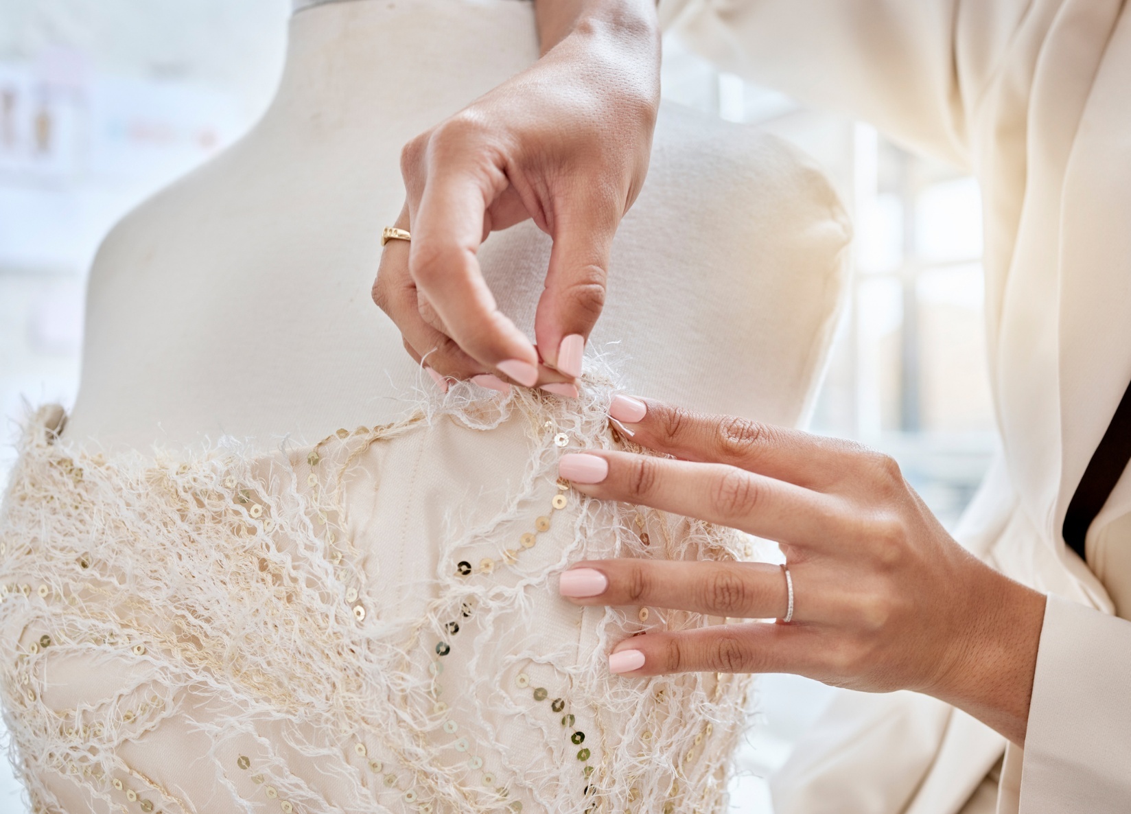 Designer with needle altering the top of a strapless wedding dress on a mannequin